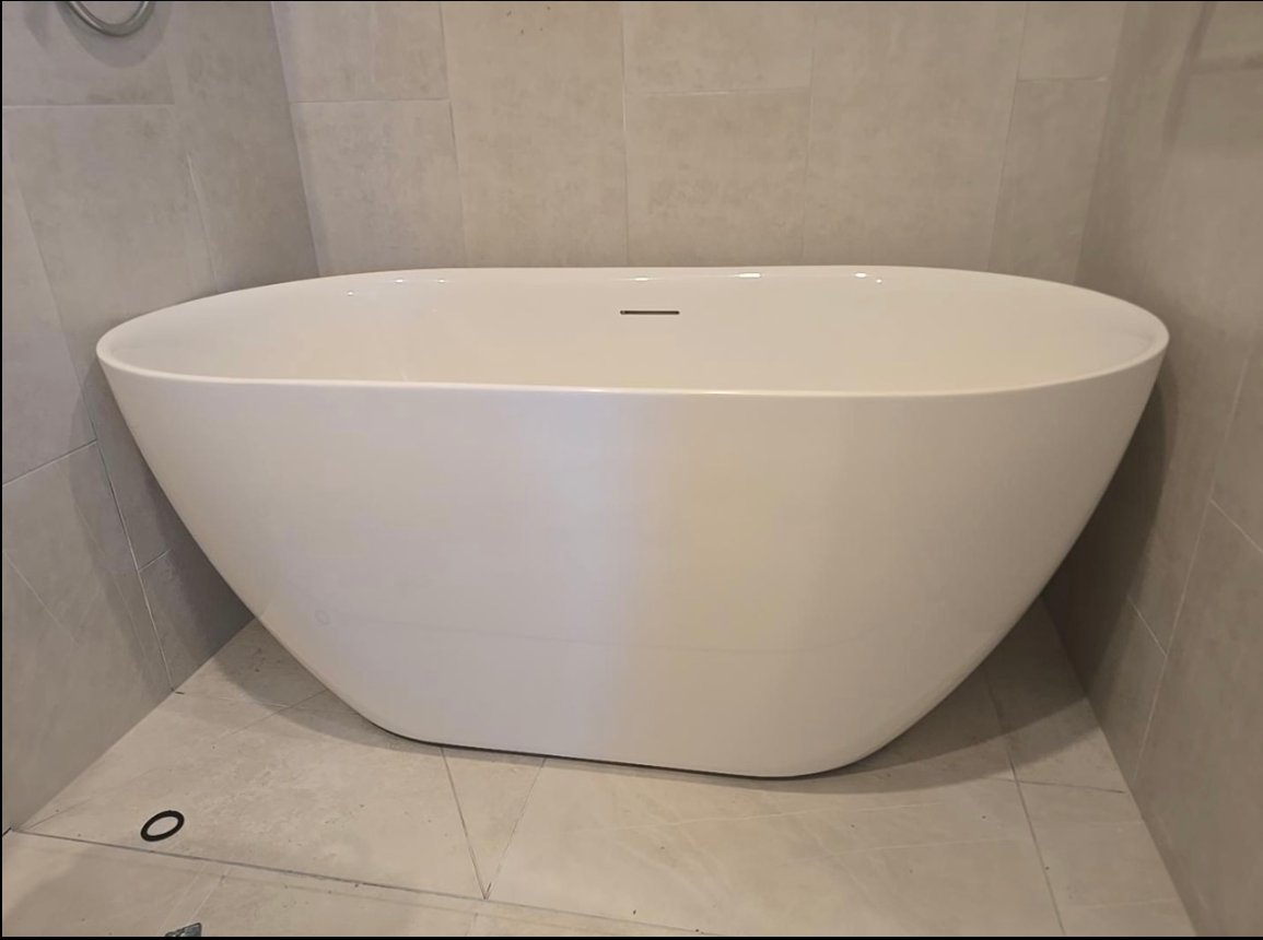 White freestanding bath against pale tiled walls
