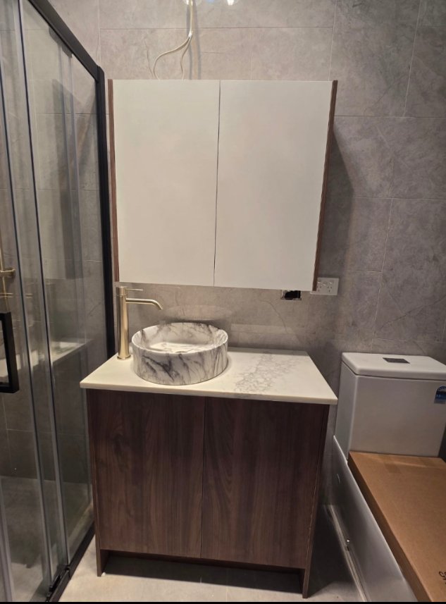 Bathroom vanity, marble-look basin and mirrored cabinet photographed during fitout