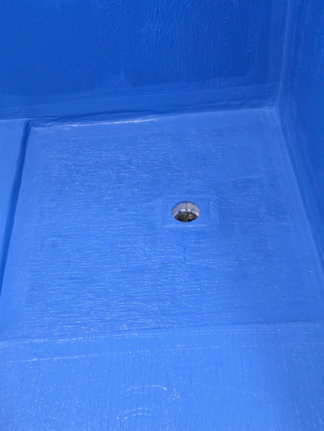 Close view of blue waterproofing membrane around shower floor waste