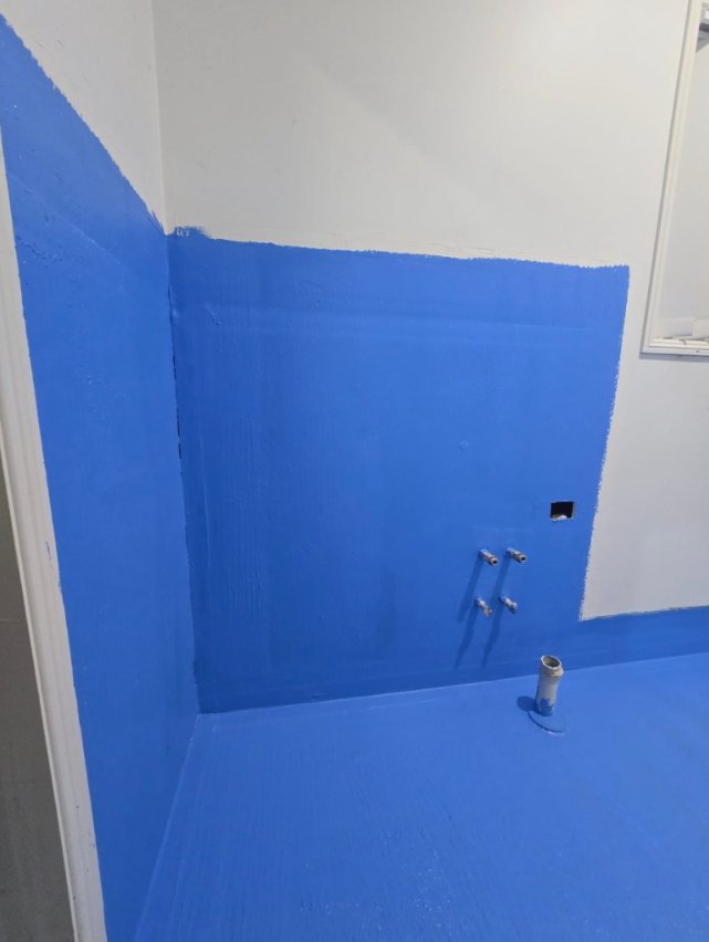 Blue waterproofing membrane meeting at bathroom wall and floor