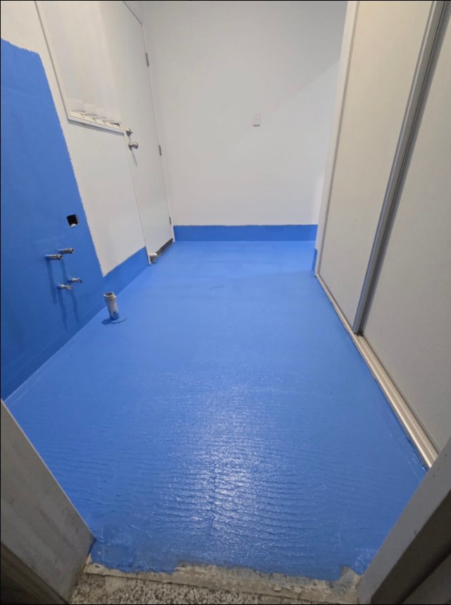 Blue waterproofing membrane across a bathroom floor and perimeter