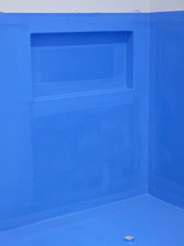 Blue waterproofing membrane around a recessed shelf and wall corner